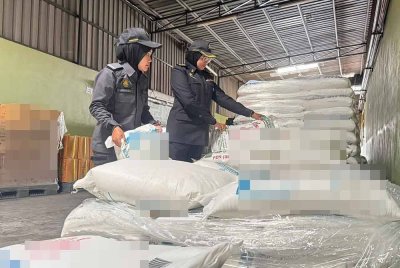 Pegawai penguat kuasa KPDN Perak memeriksa beg mengandungi tepung gandum yang disimpan melebihi had di sebuah kilang biskut di Gunung Rapat di Ipoh pada Rabu.