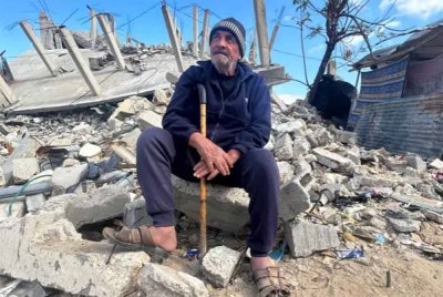 Fathi Abu al-Saeed duduk bersebelahan rumahnya yang hancur berkecai dibedil rejim Zionis di Khan Younis. Foto Agensi