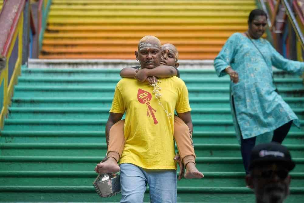 Penganut agama Hindu Mohan Raj, 35, mendukung anaknya Tharaav Raj, 6, turun daripada Kuil Batu Caves selepas selesai melakukan upacara keagamaan sempena sambutan perayaan Thaipusam yang akan disambut pada 11 Februari ini.