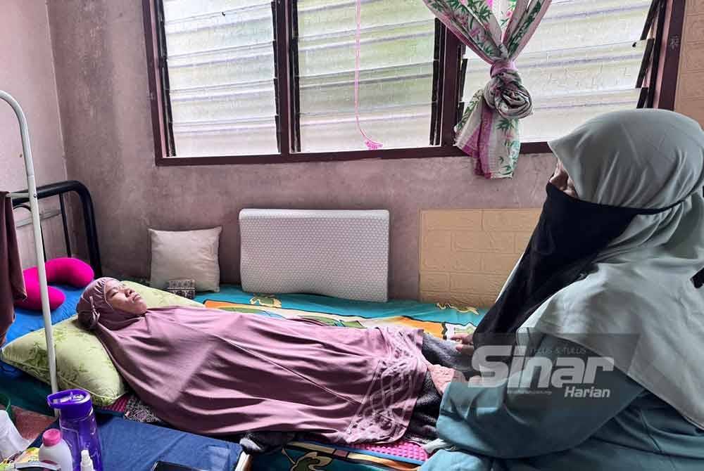 Kamariah melihat keadaan Nor Eishaty Rhadiah di rumahnya di Kampung Chengal Lempong pada Jumaat.