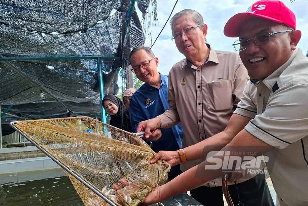 Mohammad Nizar (tengah) melihat hasil benih ikan yang dihasilkan Pusat Pembenihan Ikan Air Tawar HTA Aquatech di Kampung Changkat Tualang dekat Gopeng pada Jumaat.