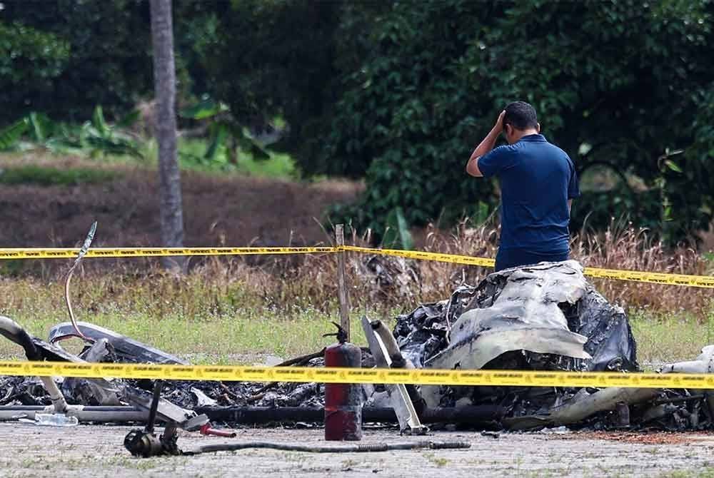 Reaksi sedih Juruterbang Kustiadi, 44, (kiri) selepas melihat helikopter jenis Bell 206L4 yang diterbangkannya terbakar selepas hilang kawalan ketika melakukan pendaratan berada di lokasi kejadian untuk meneruskan lagi siasatan punca nahas itu, pada Jumaat. Foto Bernama