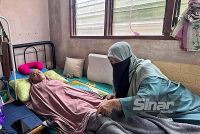 Kamariah menguruskan Nor Eishaty Rhadiah yang terlantar selepas menderita kanser paru-paru tahap empat di rumahnya di Kampung Chengal Lempong pada Jumaat.