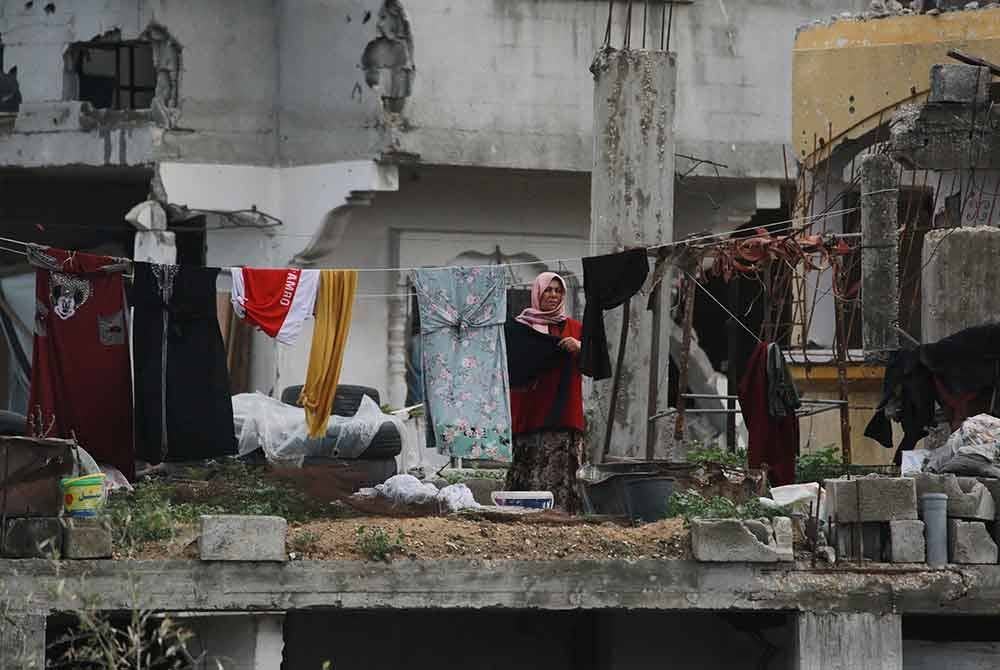 Seorang wanita Palestin menggantung pakaian yang dibasuh di sebuah bangunan yang rosak teruk di Jabalia di utara Semenanjung Gaza.