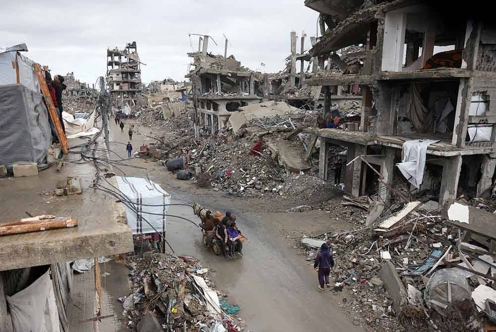 Rakyat Palestin menggunakan kereta keldai untuk tujuan pengangkutan melalui jalan yang dikelilingi bangunan yang rosak teruk akibat dibom Zionis.