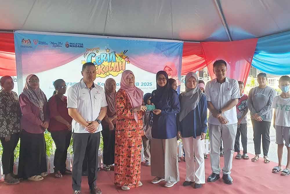 Fadhlina (tengah) menyampaikan sumbangan sempena Program Ceria Ke Sekolah Tenaga Nasional Berhad (TNB) di Pusat Khidmat Parlimen Nibong Tebal di sini, pada Sabtu.