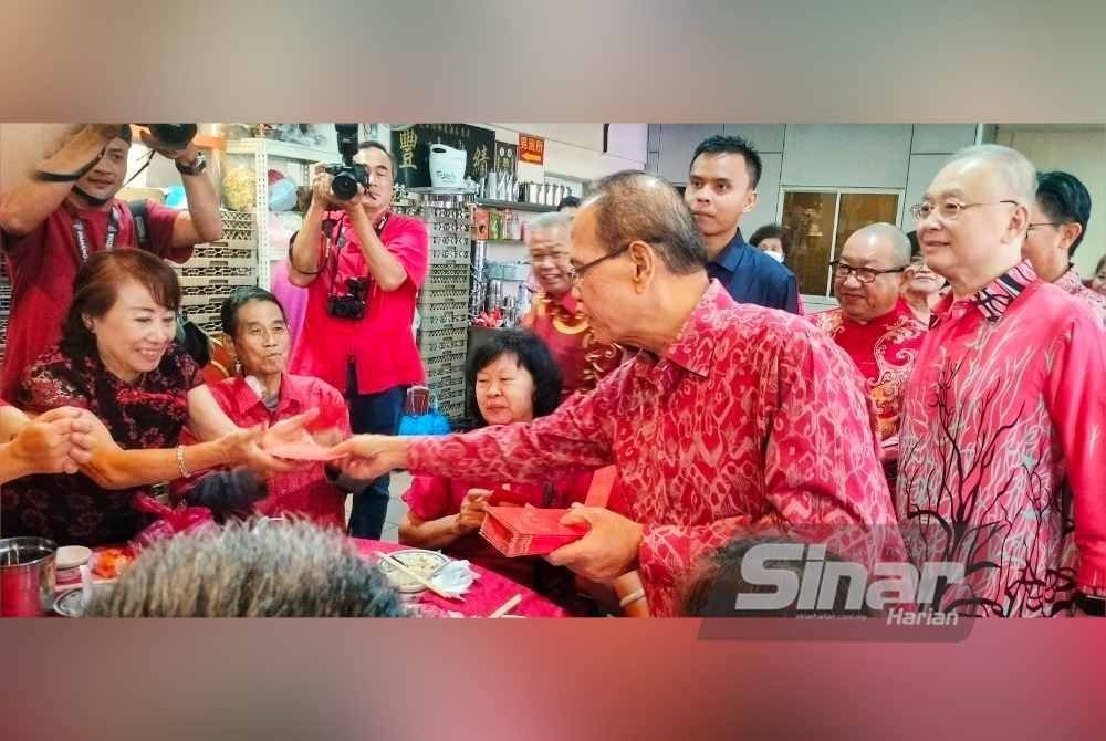 Wan Rosdy (dua dari kanan) menyerahkan angpau kepada penerima. Foto Sinar Harian