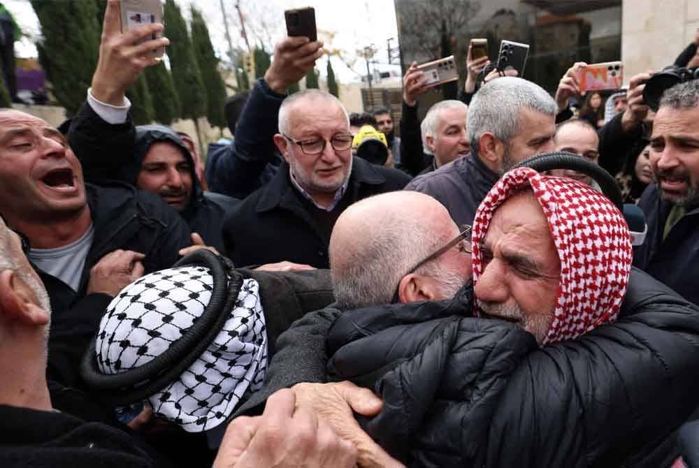 Seorang bekas tahanan Palestin memeluk ahli keluarganya selepas keluar dari sebuah bas di bandar Ramallah, Tebing Barat yang diduduki pada 8 Februari 2025, sebagai sebahagian daripada pertukaran tawanan-ke-tahanan kelima di bawah gencatan senjata Gaza yang rapuh. Foto AFP