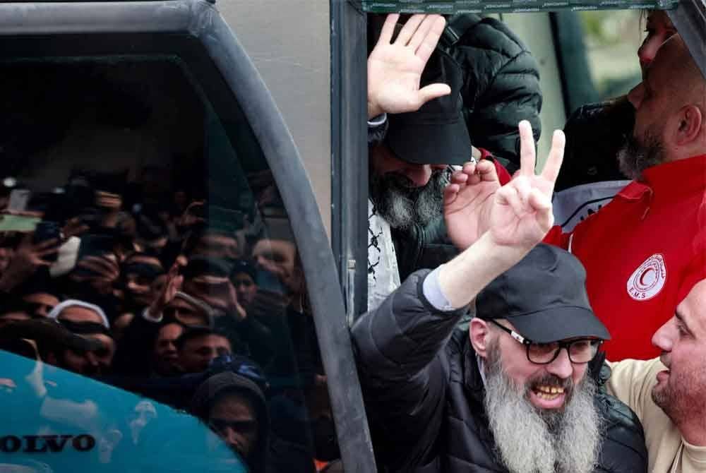 Seorang bekas tahanan Palestin yang dibebaskan oleh Israel menunjukkan isyarat kemenangan ketika beliau meninggalkan sebuah bas di bandar Ramallah, Tebing Barat yang diduduki pada 8 Februari 2025, sebagai sebahagian daripada pertukaran tawanan-ke-tahanan kelima di bawah gencatan senjata Gaza yang rapuh. Foto AFP