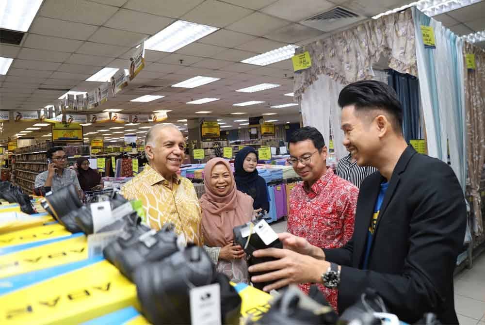 Kevin (kanan) memberi penerangan kasut ABARO yang turut dipasarkan di Mydin.
