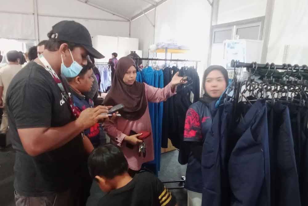 Mohd Firdaus (kiri) membeli pakaian sekolah anak sulungnya yang berusia tujuh tahun.