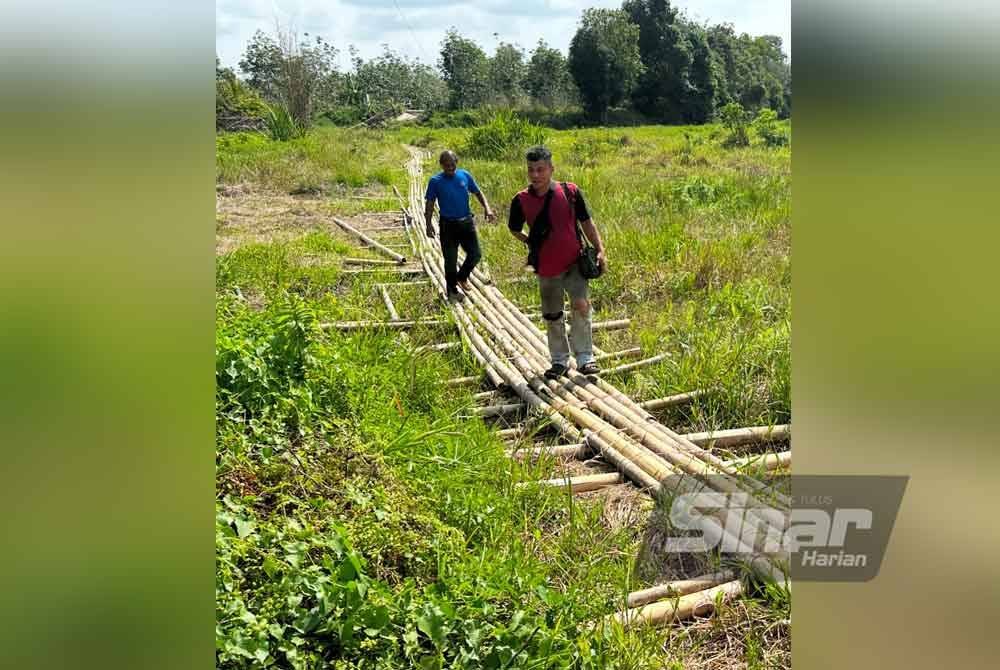 Mohd Zulkifli (kanan) dan Rukman yang menggunakan titi buluh untuk menyeberangi Sungai Mahligai. FOTO SINAR HARIAN-ADILA SHARINNI WAHID