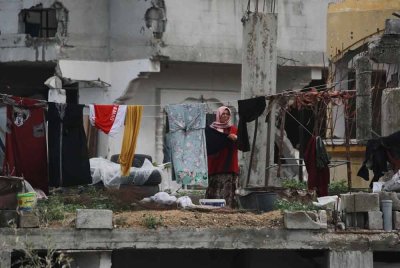 Seorang wanita Palestin menggantung pakaian yang dibasuh di sebuah bangunan yang rosak teruk di Jabalia di utara Semenanjung Gaza.