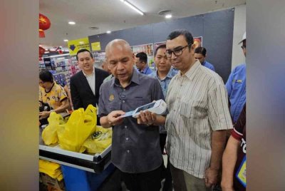 Armizan menggunakan MyKad untuk membuat semakan untuk program SAR di salah sebuah premis pasar raya di Penampang.