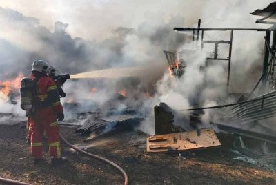 Anggota bomba memadamkan api di sebuah rumah yang musnah terbakar di Kampung Parit Sakai Darat, Muar awal pagi tadi. Foto BBP Muar