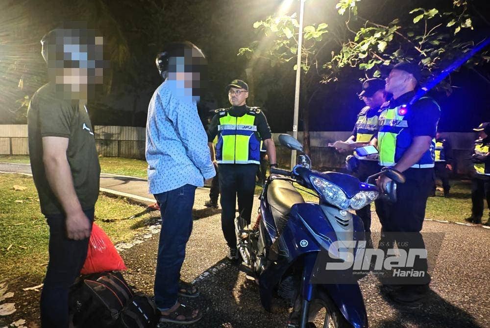 Hanif Yusabra (tiga dari kanan) bertanya sesuatu kepada penunggang motosikal yang ditahan.