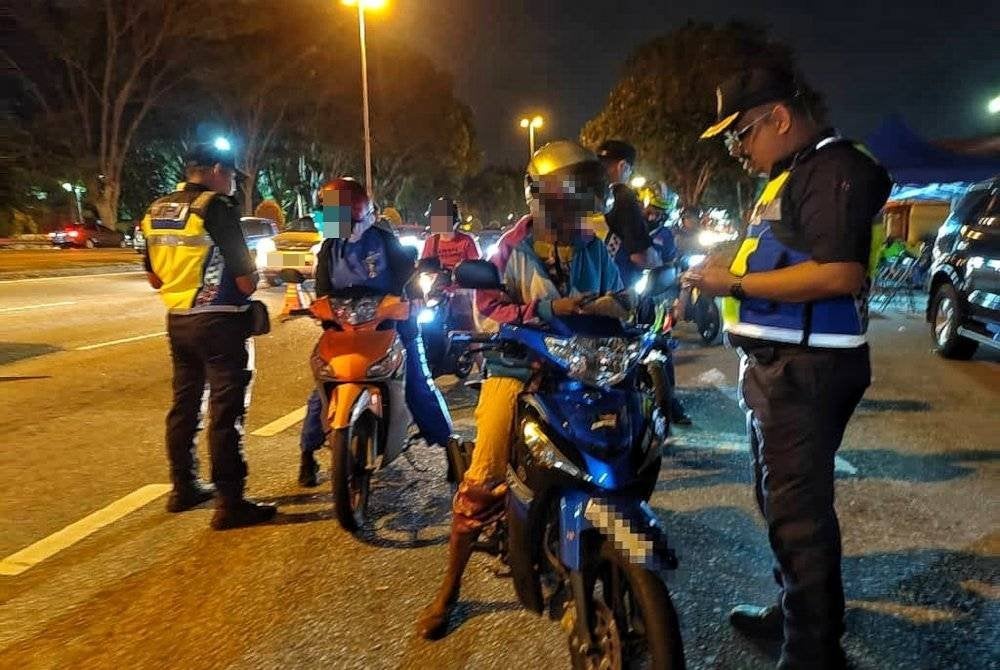 Muhammad Firdaus (kanan) memeriksa lesen motosikal seorang wanita yang ditahan dalam Operasi Khas Tahun Baru Cina 2025 di Lebuh AMJ pada malam Ahad.