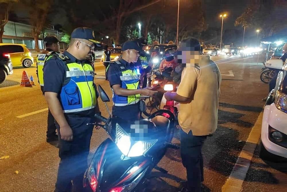 Muhammad Firdaus (kiri) menyoal siasat seorang penunggang motosikal disyaki mabuk dalam operasi itu.