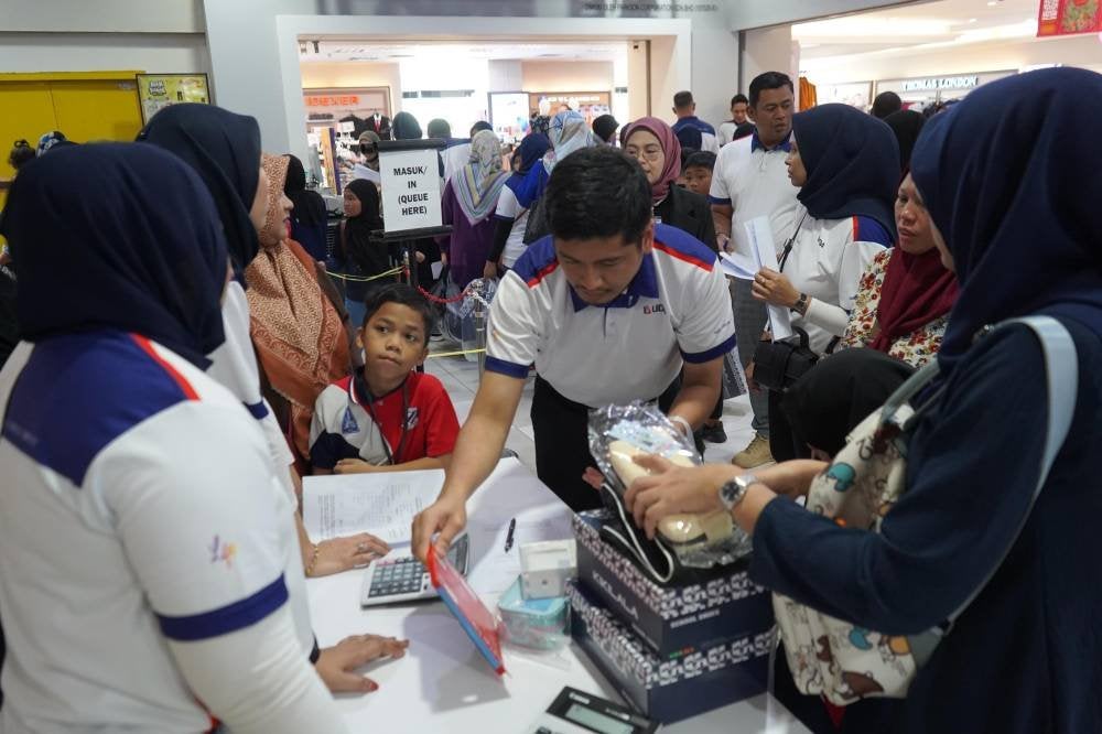 Wargakerja UDA membantu pelajar membeli-belah kelengkapan persekolahan di Angsana Johor Bahru Mall.