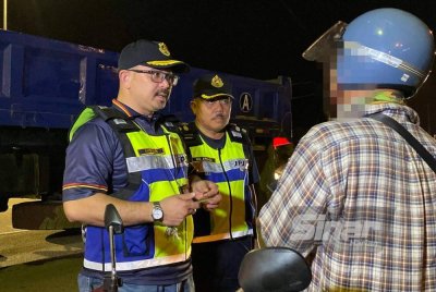 Mohd Misuari (kiri) memeriksa penunggang motosikal semasa Penutup Operasi Khas Tahun Baharu Cina yang diadakan di JPJ Bukit Jawa, Pasir Puteh pada Ahad malam.