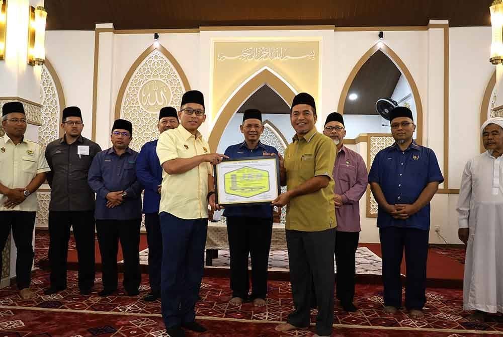 Aminuddin (tengah) melihat gimik penyerahan projek Masjid Bukit Kepayang oleh aznor Izman kepada Noor Ihsan.