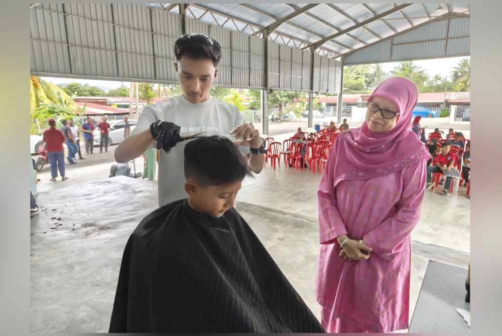 Tengku Zamrah (kanan) bertanyakan sesuatu kepada peserta Program Gunting Rambut Percuma pada Selasa.
