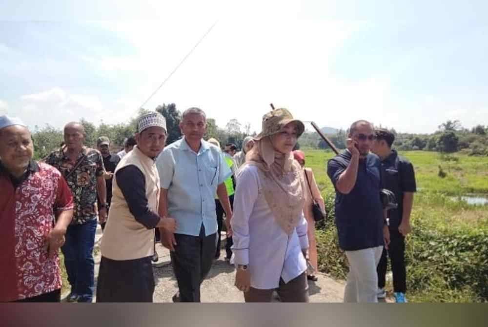 Siti Fairus (depan) meninjau kawasan jambatan runtuh di Kampung Rong Chenok pada Selasa.