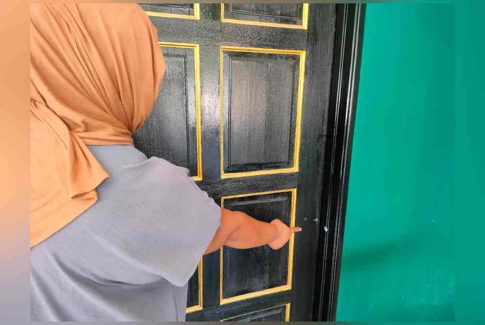 Dian menunjukkan kesan tembakan pada bingkai pintu rumahnya.