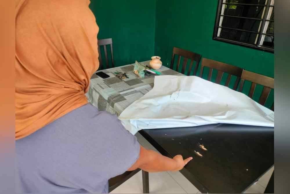 Dian menunjukkan kesan tembakan di meja makan di rumahnya.