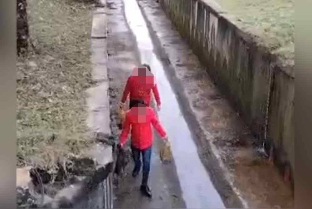 Tangkap layar rakaman dua individu membawa bungkusan berisi ular sawa sebelum dilepaskan dalam longkang di Jalan Persiaran Putra Permai, Putra Height.