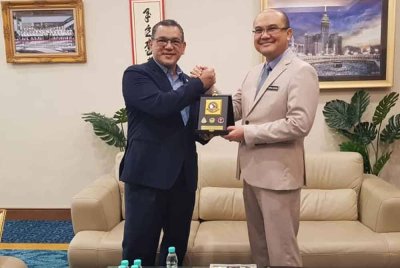 Nizam (kiri) menerima cenderahati daripada Jamaluddin dalam kunjungan hormat di pejabatnya di Menara Kinabalu.