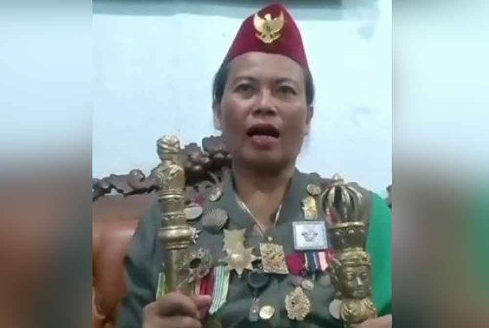 'Ratu Sedunia' memegang tongkat dan mengenakan baju berwarna hijau lumut bersama sejumlah pingat.