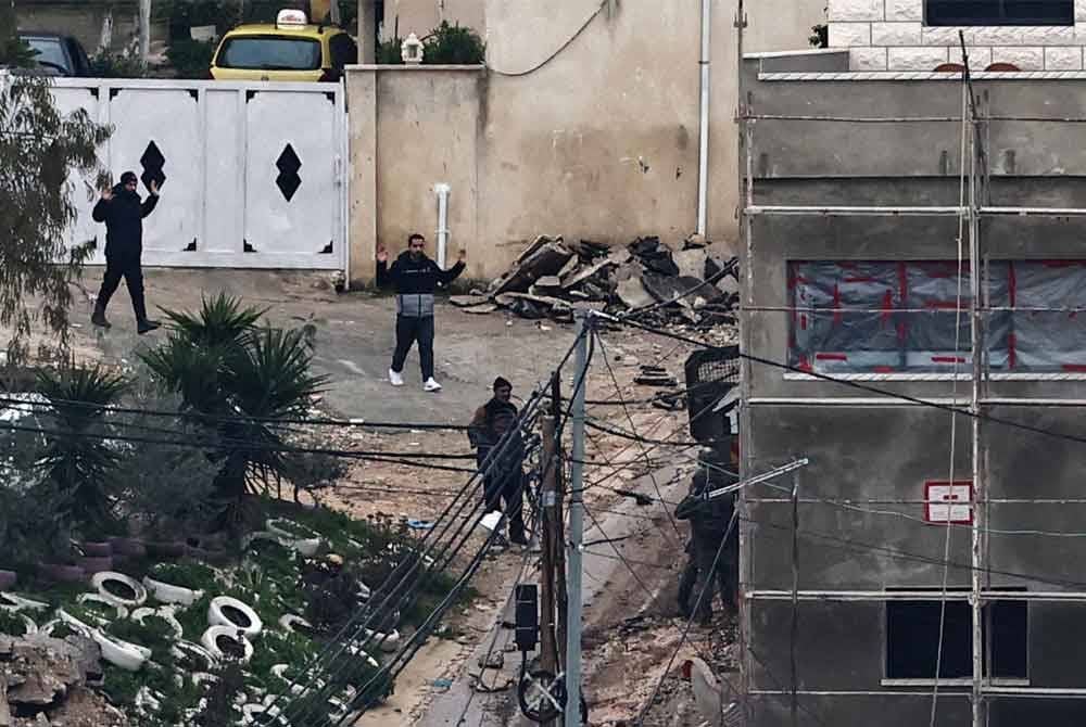 Penduduk Palestin mengangkat tangan kerana bimbang menjadi sasaran penembak tepat di sekitar Tebing Barat.