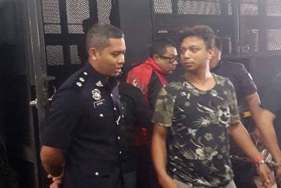 Muhammad Ihsan (kanan) dibawa polis ke Mahkamah Butterworth pada Rabu.