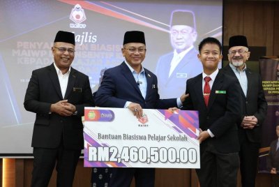 Mohd Na'im (dua dari kiri) menyampaikan sumbangan Bantuan Biasiswa Pelajar Sekolah kepada Muhammad Rizqi Mohd Jasiman (dua, kanan) pada Majlis Sumbangan Biasiswa Majlis Agama Islam Wilayah Persekutuan (MAIWP) dan Insentif Khas kepada pelajar asnaf di Maktab Rendah Sains MARA (MRSM) dan Sekolah Berasrama Penuh (SBP) di Menara MAIWP pada Rabu. Foto Bernama