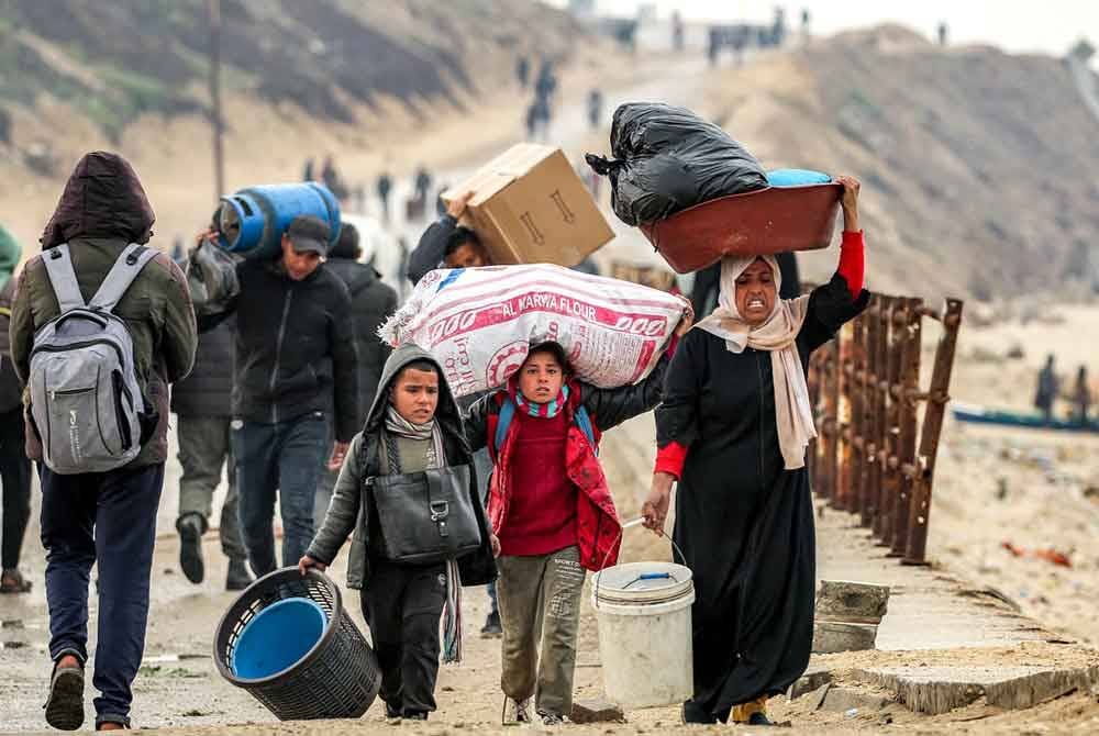Penduduk Gaza membawa barangan peribadi dilihat berjalan menuju ke rumah masing-masing di Genting Gaza selepas gencatan senjata dipersetujui antara Hamas-Israel. - AFP
