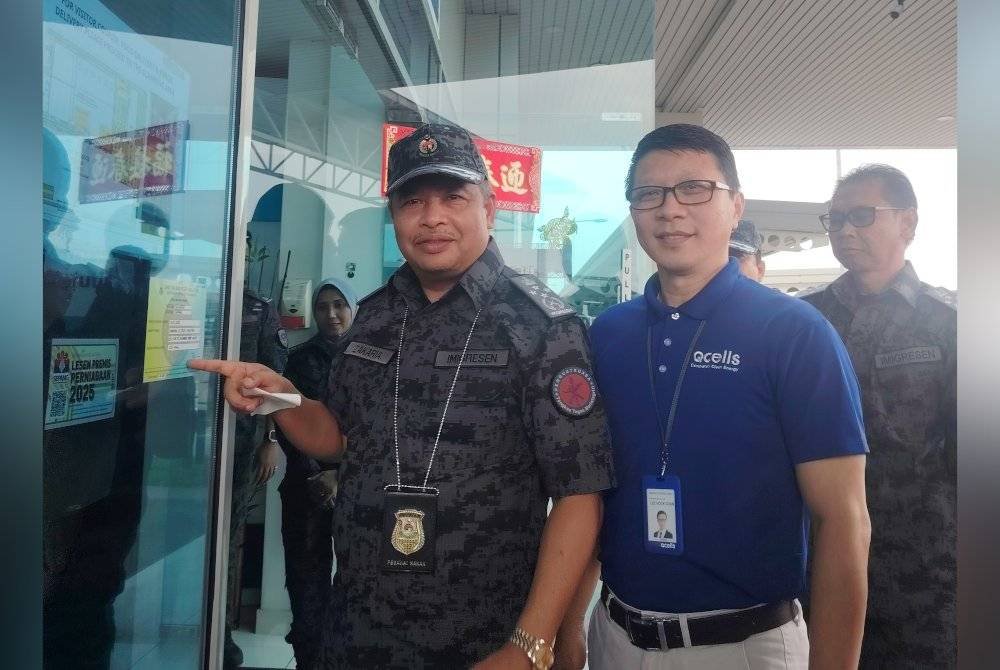 Zakaria (kiri) menunjukkan pelekat simbolik Program Inspektorat Penguatkuasaan di sebuah syarikat di Cyberjaya pada Khamis.