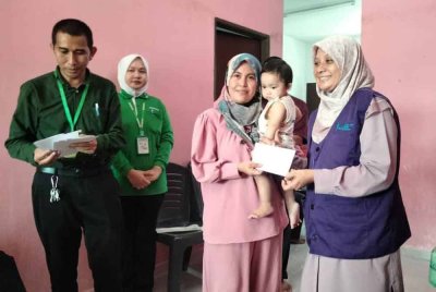 Dr Dasmawati (kanan) menyampaikan bantuan kepada seorang penerima baucar