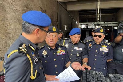 Aedy Fadly (dua dari kiri) bersama Azman (kiri) hadir di salah sebuah premis di Puchong untuk operasi pemeriksaan tayar celup pada Khamis.
