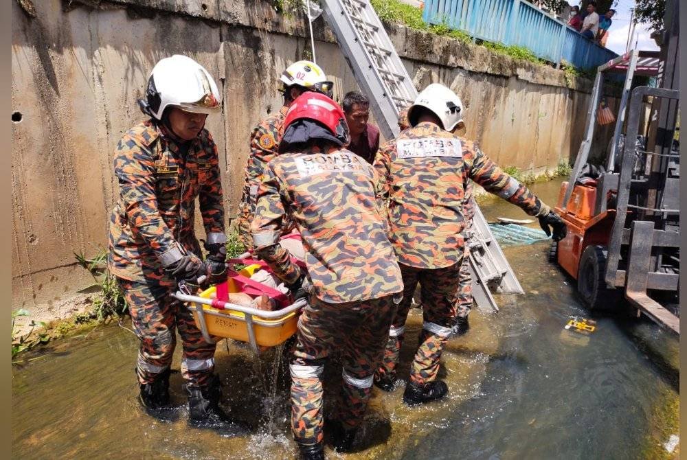 Anggota bomba mengangkat mangsa setelah terjatuh ke dalam longkang.