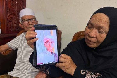 Ruhani (kanan) di samping Wan Abdul Rahman (kiri) menunjukkan gambar arwah Wan Ahmad Faris yang tinggal sebagai kenangan buat mereka. FOTO SINAR HARIAN-ADILA SHARINNI WAHID