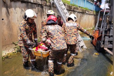 Anggota bomba mengangkat mangsa setelah terjatuh ke dalam longkang.