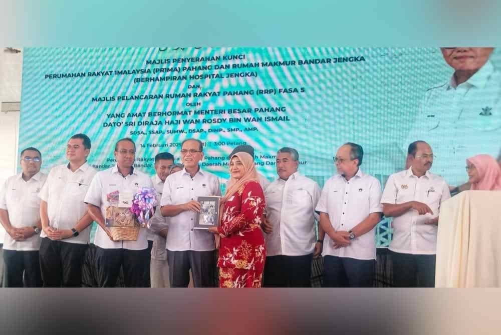 Wan Rosdy (empat dari kiri) menyerahkan kunci kepada penerima rumah projek terbabit di Bandar Jengka pada Jumaat.