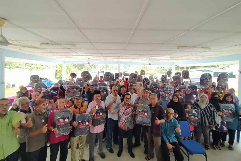 Mazlan (lapan dari kiri) bersama sebahagian daripada 160 penerima sumbangan beg sekolah dan alat tulis sempena Program Bantuan Kembali Ke Sekolah di Dewan Komuniti Taman Berjaya, Tanjung Rambutan di sini pada Sabtu.