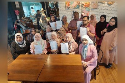 Siti Suwaibah (duduk dua dari kiri) bersama sebahagian daripada mangsa menunjukkan laporan polis dibuat mereka ketika sidang akhbar di Putrajaya pada Sabtu.