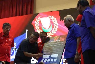 Saifuddin Nasution (tengah) menandatangani resolusi Konvensyen Perpaduan Kedah pada Sabtu.