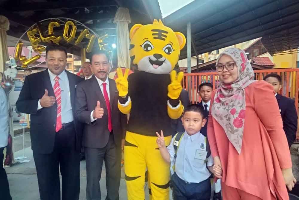 Nik Nur Aisyah (kanan) membawa anaknya pada hari pertama persekolahan di SK Ismail 1 pada Ahad.