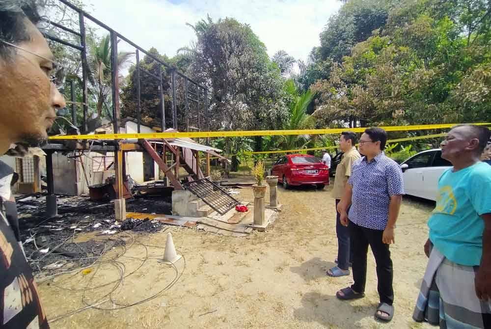 Khairul Azwan (dua dari kanan) melihat keadaan rumah Mohd Razali yang musnah dalam kebakaran tersebut.