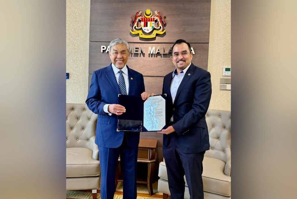 Asyraf Wajdi (kanan) menerima watikah pelantikan daripada Ahmad Zahid.