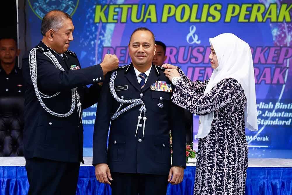 Azri (kiri) dan Noormawati (kanan) memakaikan pangkat jawatan Ketua Polis Perak kepada Noor Hisam.